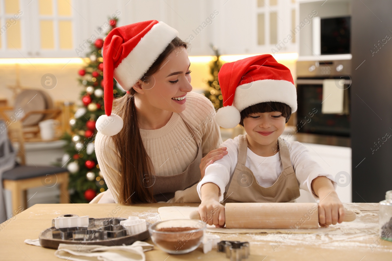 Photo of Mother with her cute little son making dough for Christmas cookies in kitchen