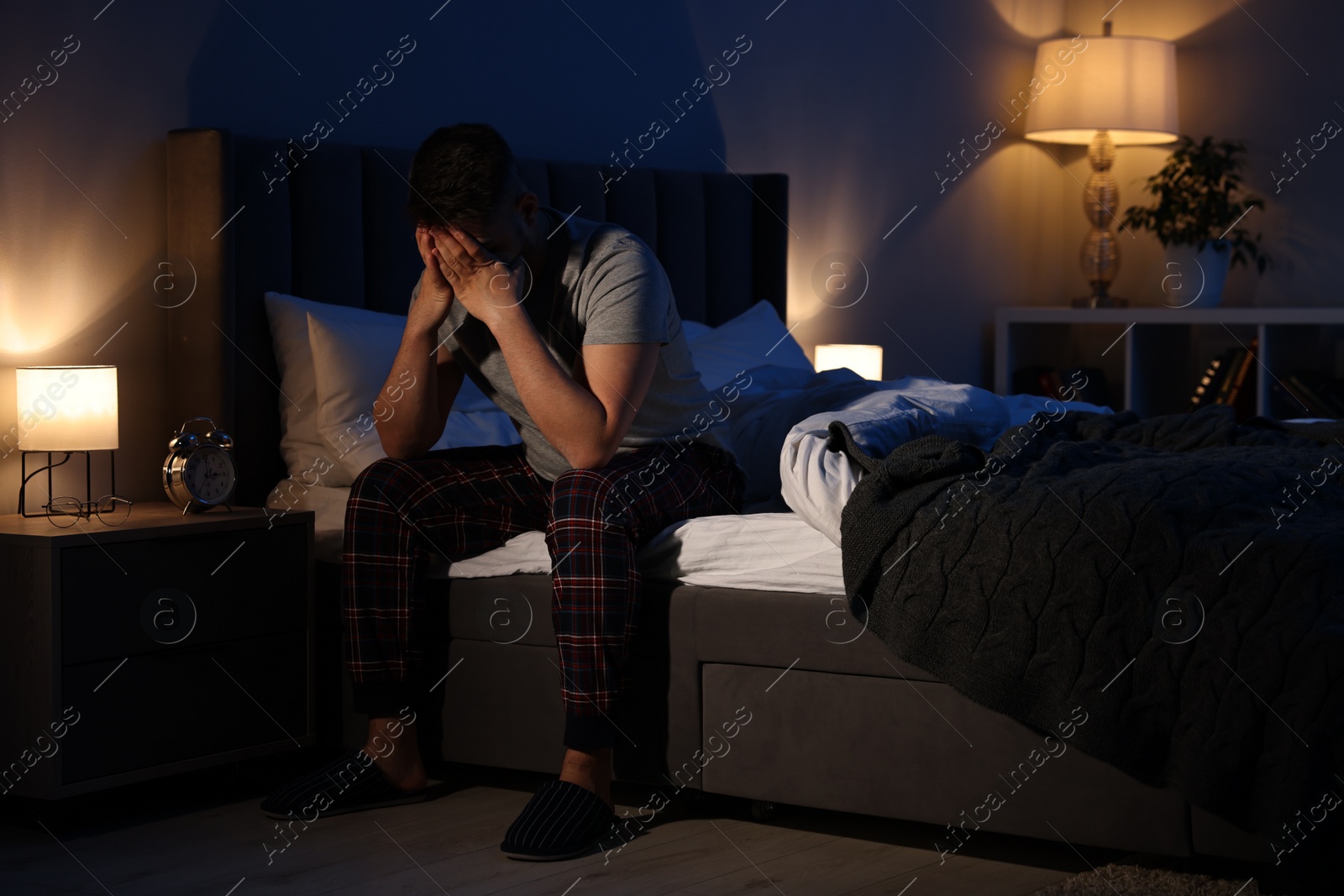 Photo of Man covering face with hands on bed