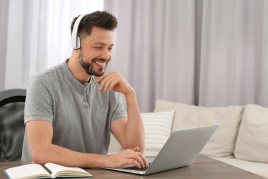 Photo of Man in headphones studying on laptop at home. Online translation course
