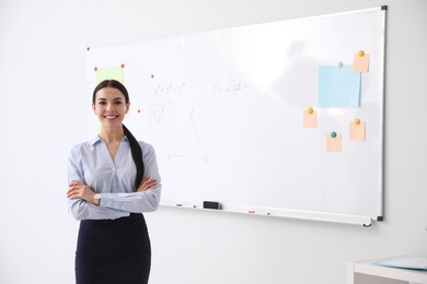 Photo of Young teacher near whiteboard in modern classroom. Space for text