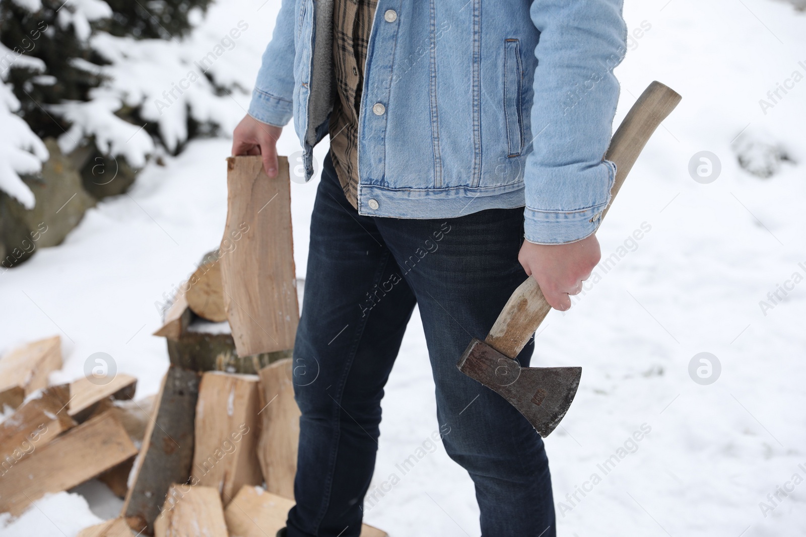 Photo of Man chopping wood with axe outdoors on winter day, closeup