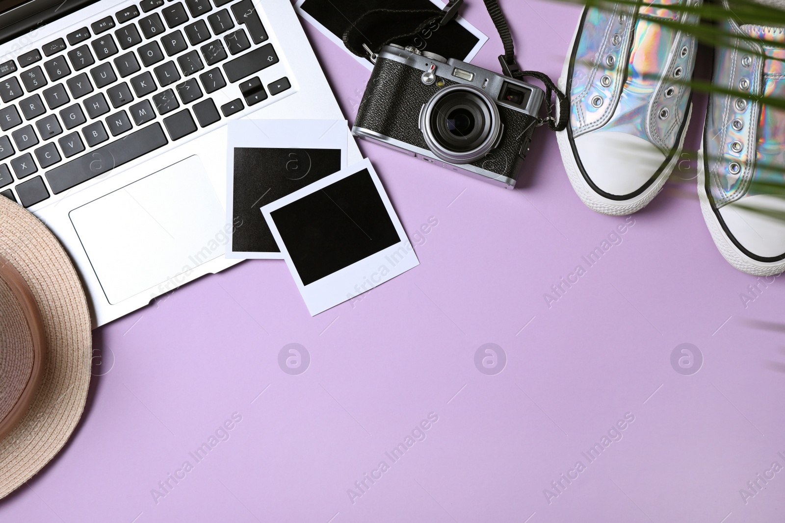 Photo of Flat lay composition with laptop and travel blogger's stuff on lilac background, space for text
