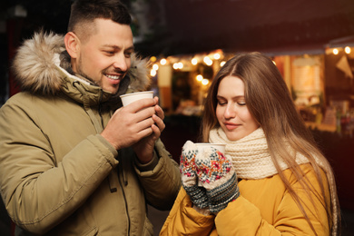Happy couple with mulled wine at winter fair