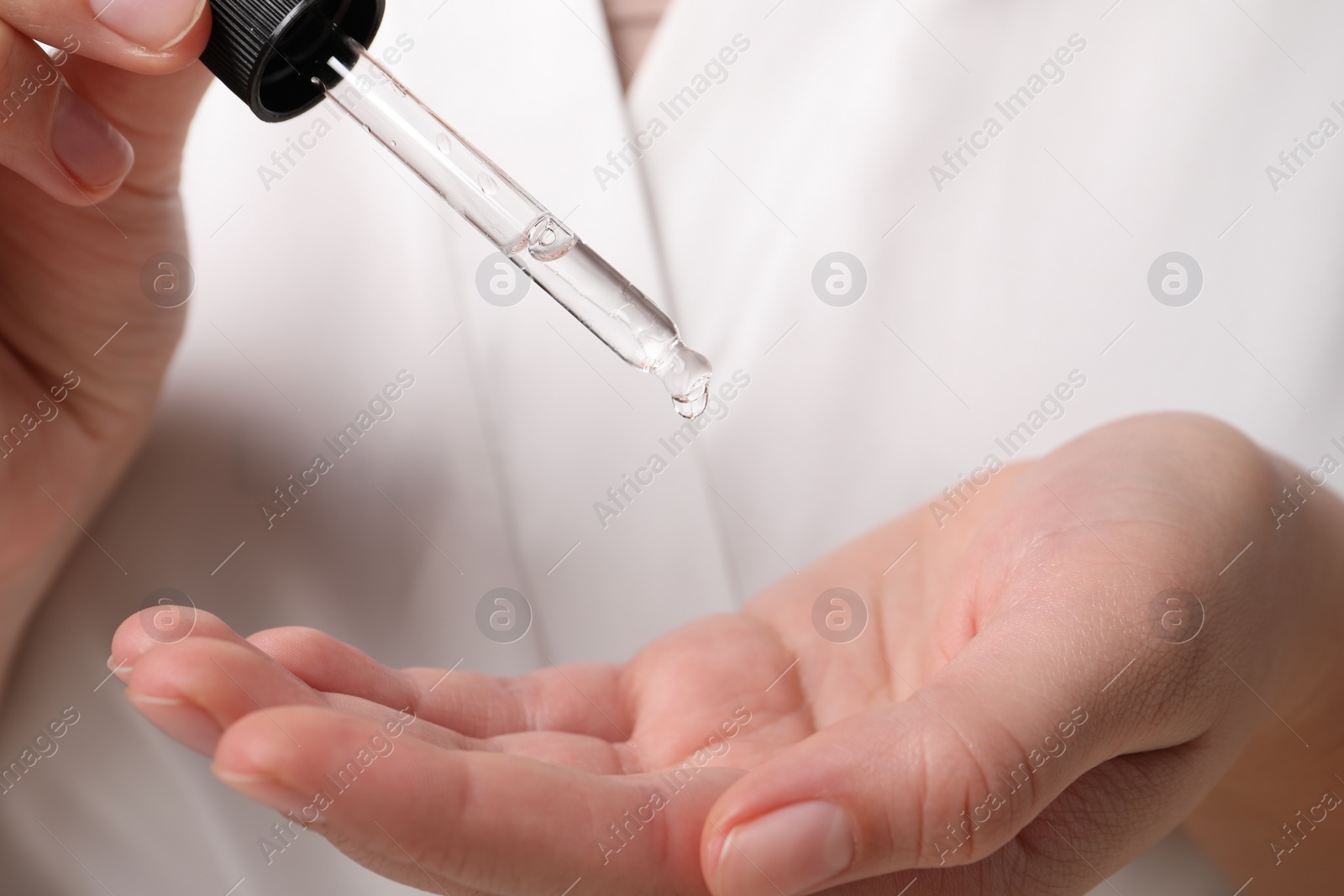 Photo of Woman applying cosmetic serum onto hand, closeup