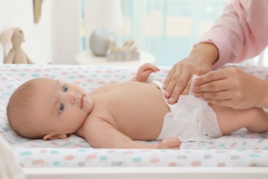 Photo of Mother changing her baby's diaper on table at home