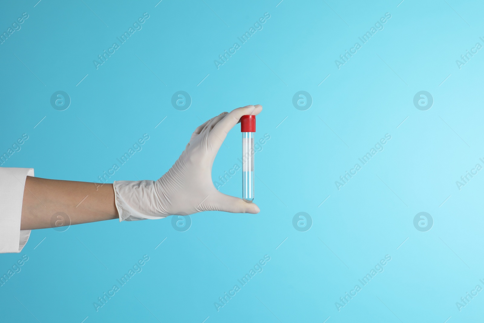 Photo of Female doctor holding empty test tube on color background, closeup view with space for text. Medical object