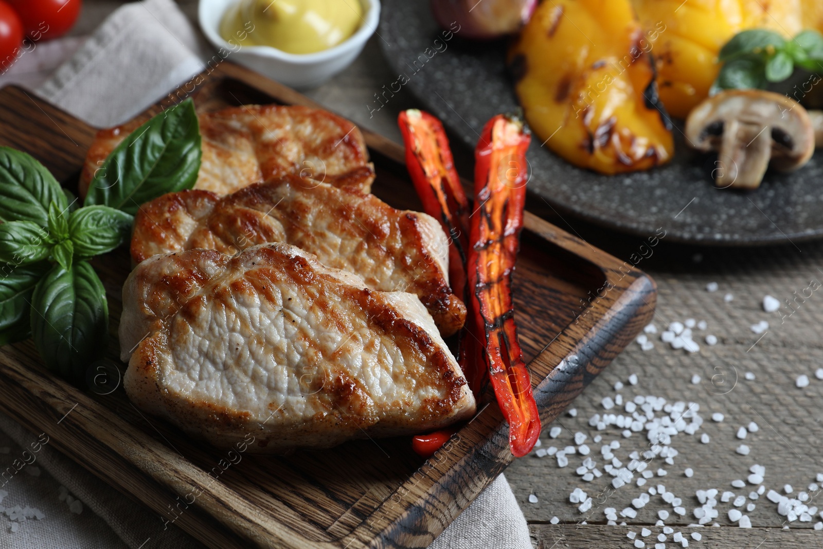 Photo of Delicious grilled meat and vegetables served on wooden table, closeup