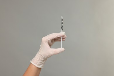 Photo of Doctor holding medical syringe on grey background, closeup