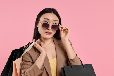 Beautiful woman with shopping bags on pink background