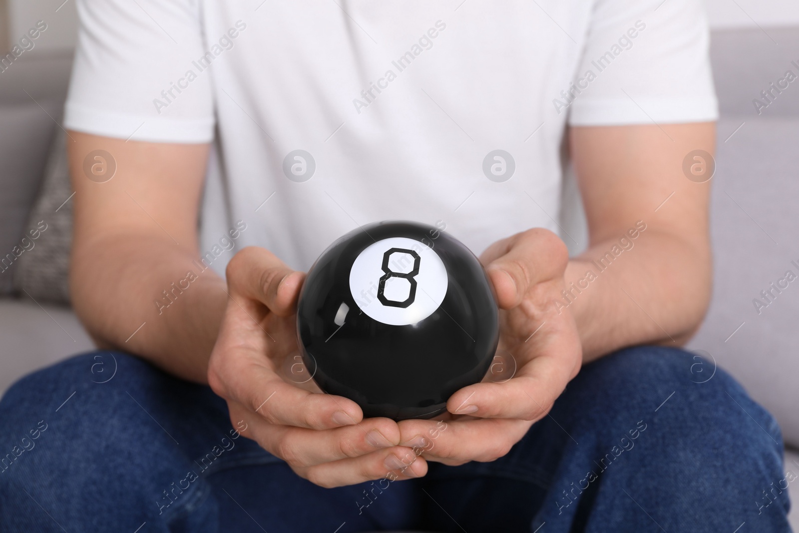 Photo of Man holding magic eight ball indoors, closeup