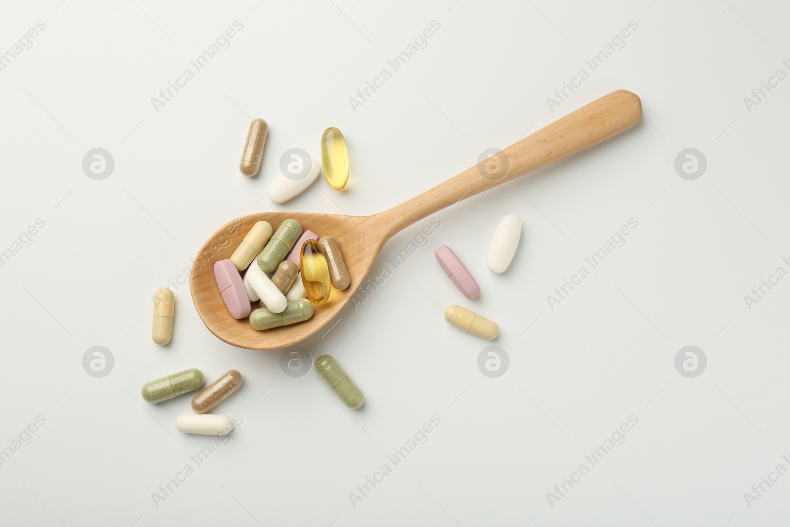 Photo of Different vitamin capsules in spoon on white background, top view