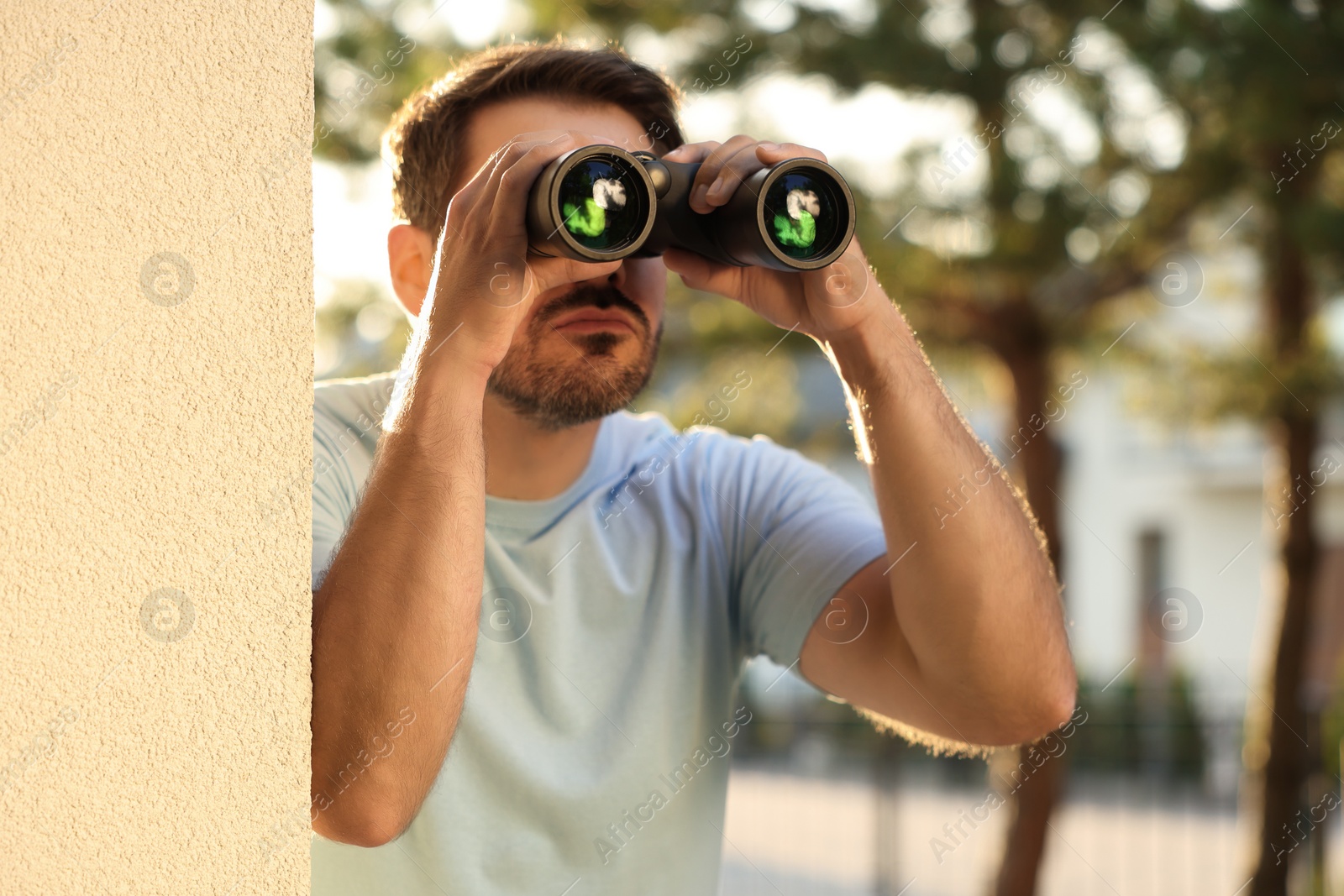 Photo of Concept of private life. Curious man with binoculars spying on neighbours outdoors