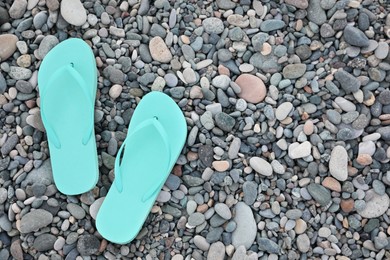 Photo of Stylish turquoise flip flops on pebble seashore, top view. Space for text