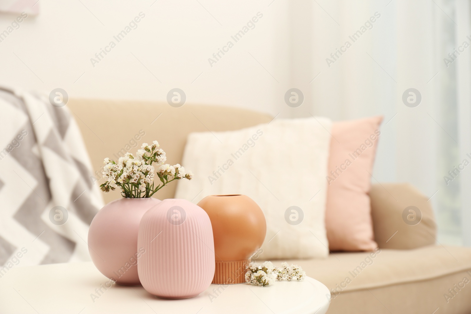 Photo of Beautiful ceramic vases and flowers on table in living room