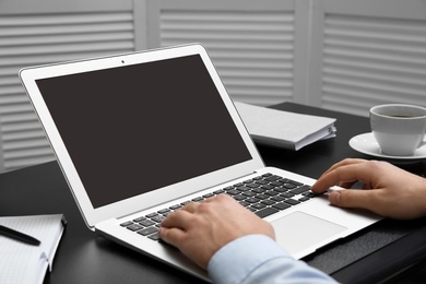 Photo of Young man using modern laptop at table, closeup