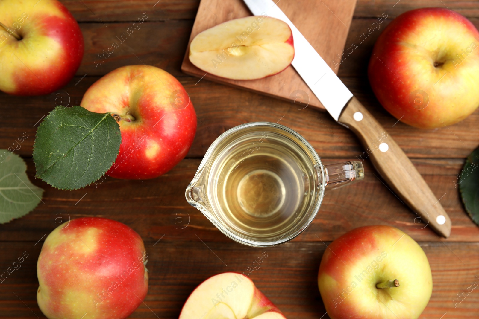 Photo of Natural apple vinegar and fresh fruits on wooden table, flat lay