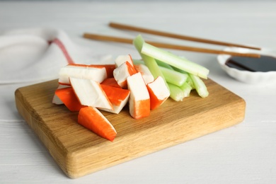 Photo of Fresh crab sticks with celery served on white wooden table