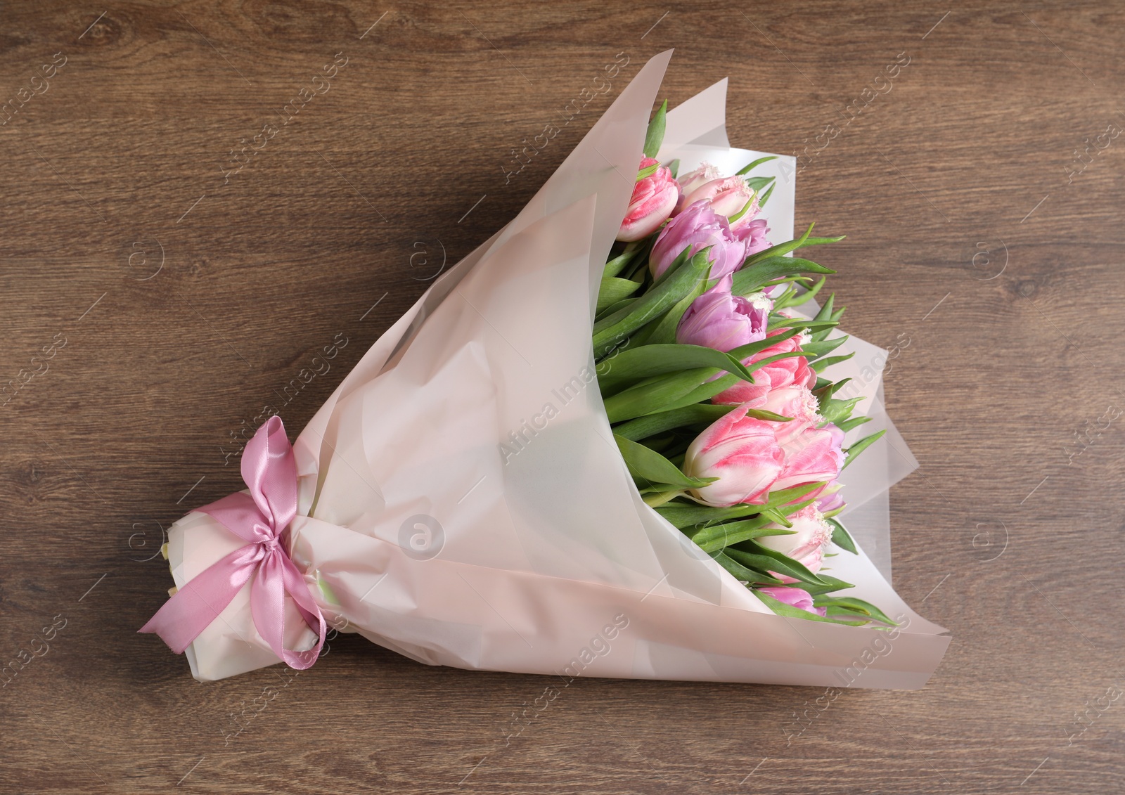 Photo of Bouquet of beautiful tulips on wooden table, top view