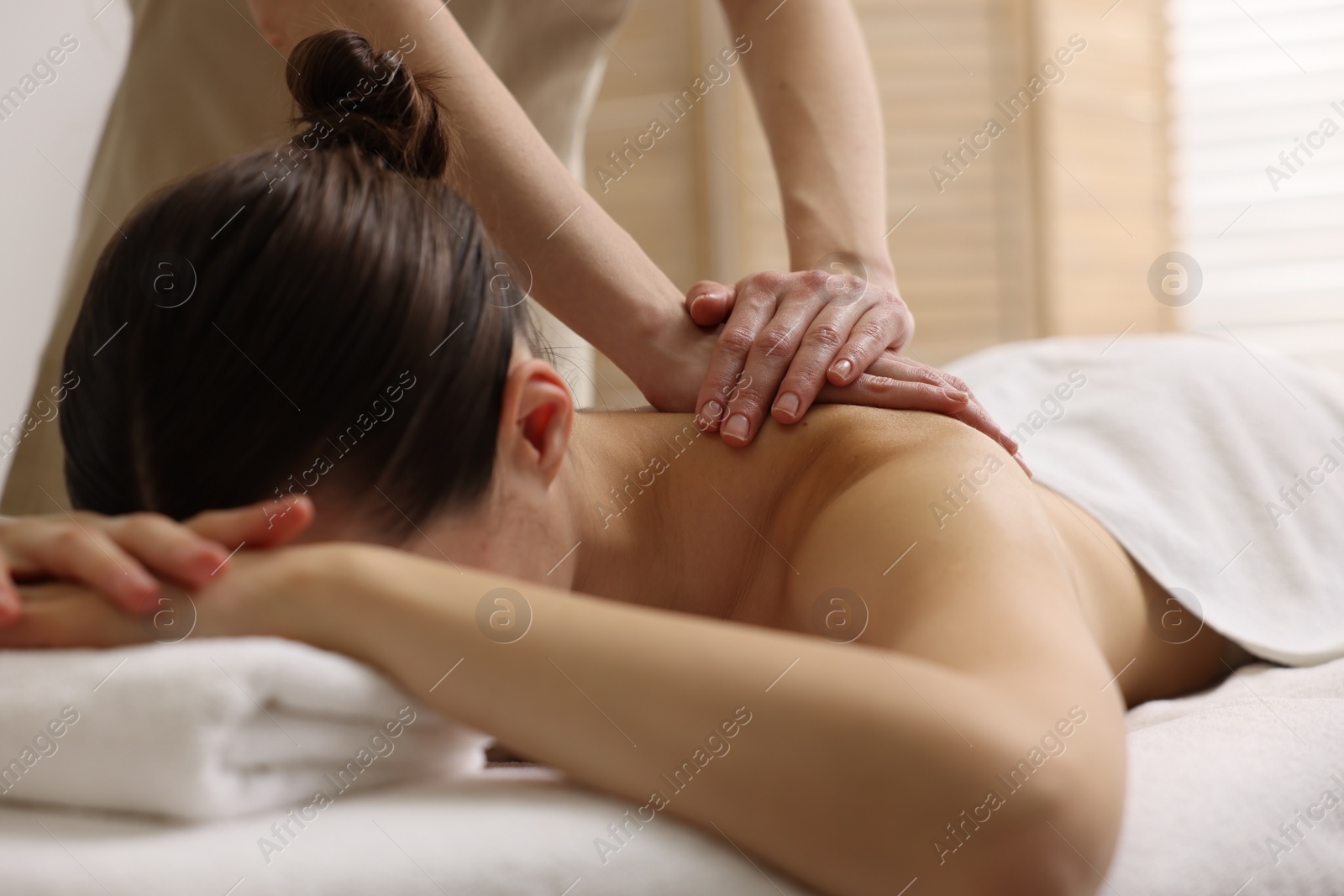 Photo of Woman receiving back massage on couch in spa salon