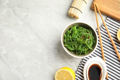 Photo of Japanese seaweed salad served on light marble table, flat lay. Space for text