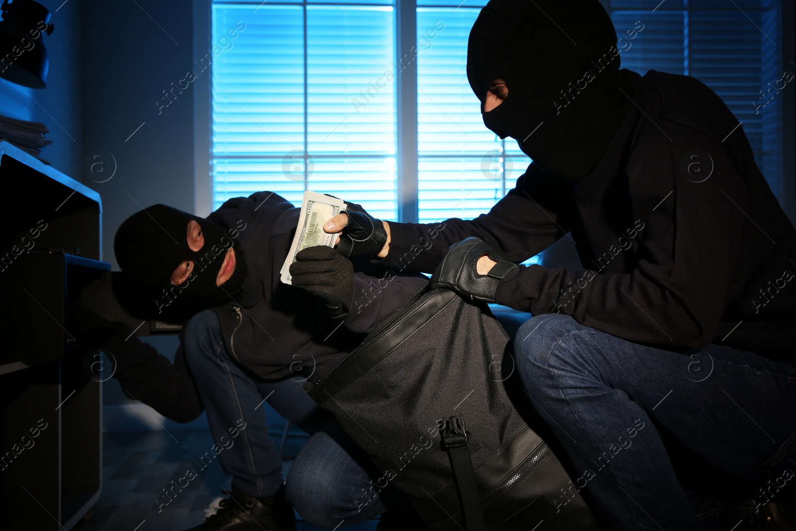 Photo of Thieves taking money out of steel safe indoors at night