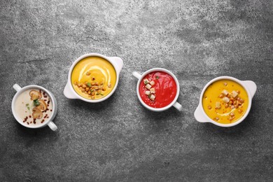 Different tasty cream soups on grey table, flat lay