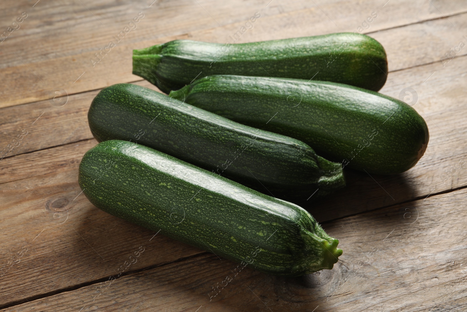 Photo of Many raw ripe zucchinis on wooden table