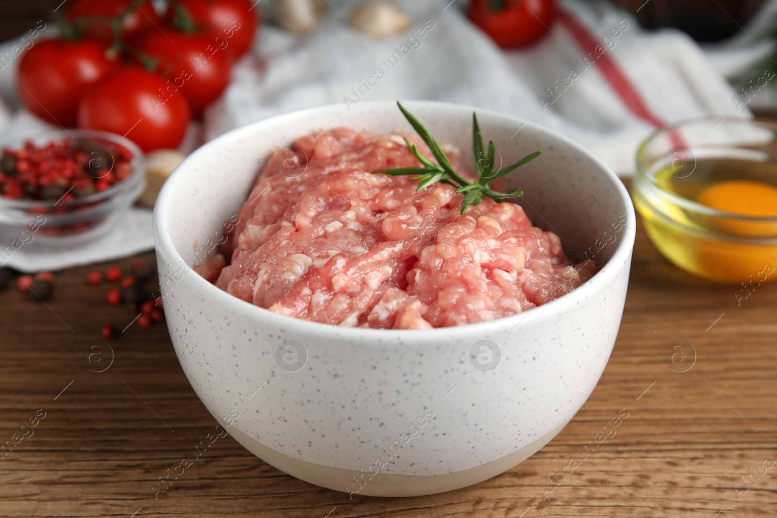 Photo of Raw chicken minced meat with rosemary on wooden table, closeup