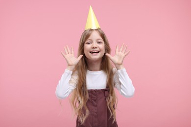 Photo of Happy little girl in party hat on pink background