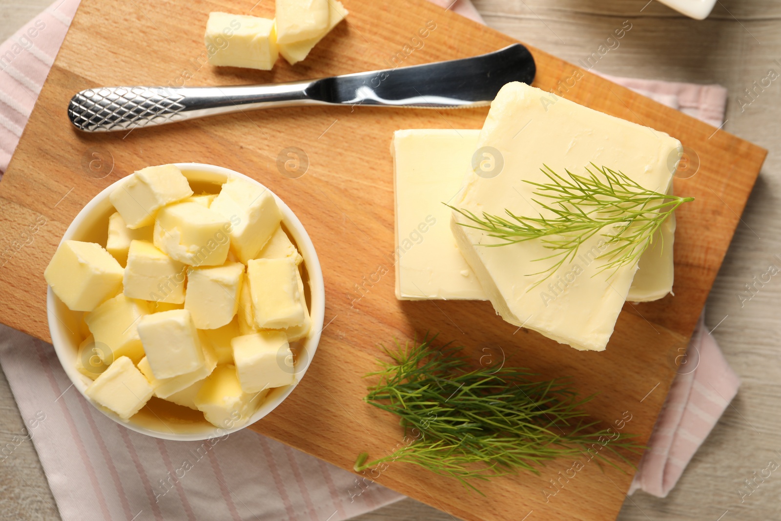 Photo of Tasty butter with dill and knife on wooden table, top view