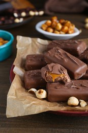 Many tasty chocolate bars and nuts on wooden table, closeup