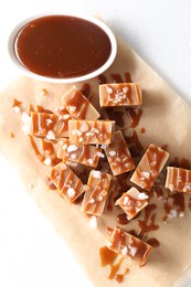 Photo of Tasty candies, caramel sauce and salt on white table, top view