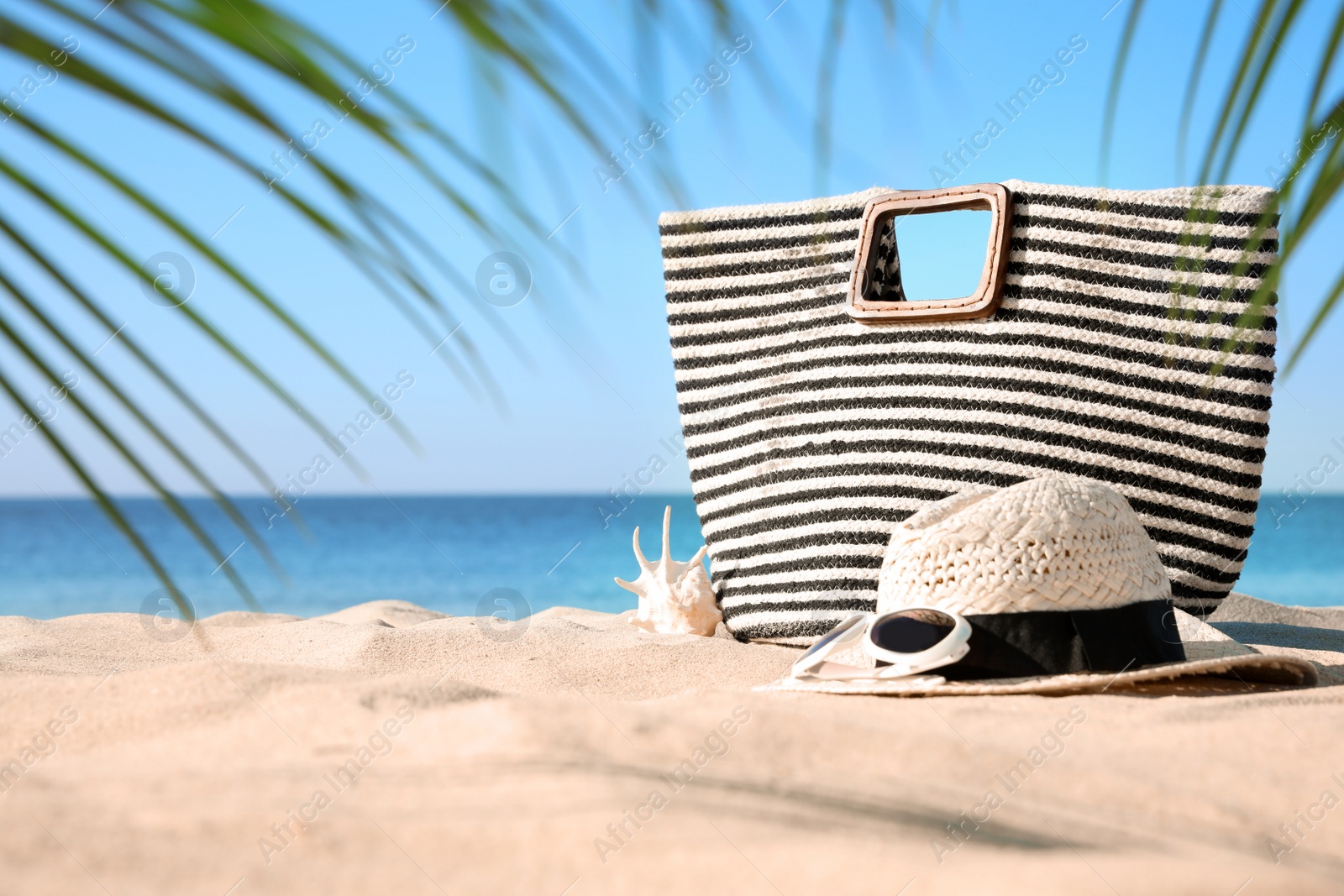 Photo of Stylish beach accessories on sand near sea