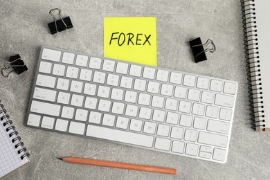 Photo of Sticky note with word Forex, keyboard, pencil and binder clips on grey table, flat lay