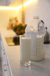 Photo of Gallon bottle of milk and glass on white countertop in kitchen