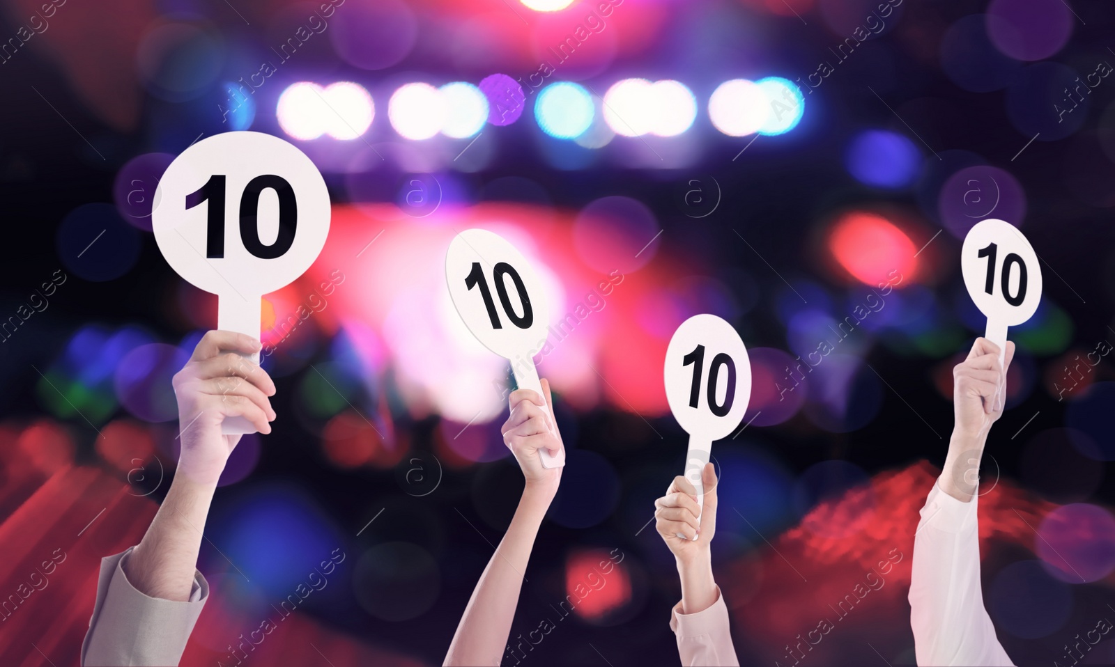 Image of Panel of judges holding signs with highest score against blurred background, closeup. Bokeh effect