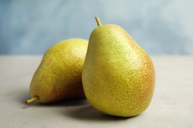 Ripe juicy pears on grey stone table against blue background, closeup