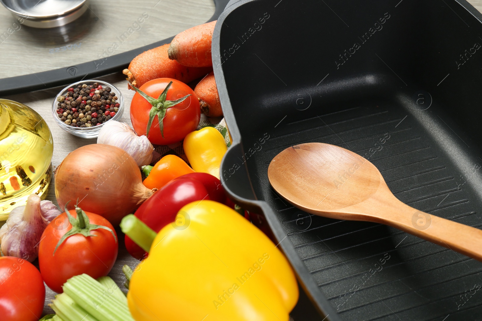 Photo of Black pot, wooden spoon and fresh products on table