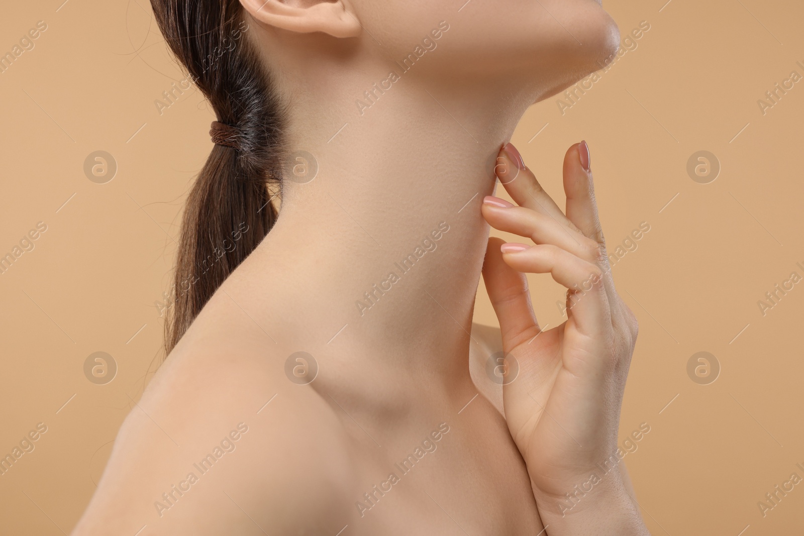 Photo of Woman touching her neck on beige background, closeup