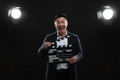 Photo of Emotional asian actor with clapperboard on stage. Film industry
