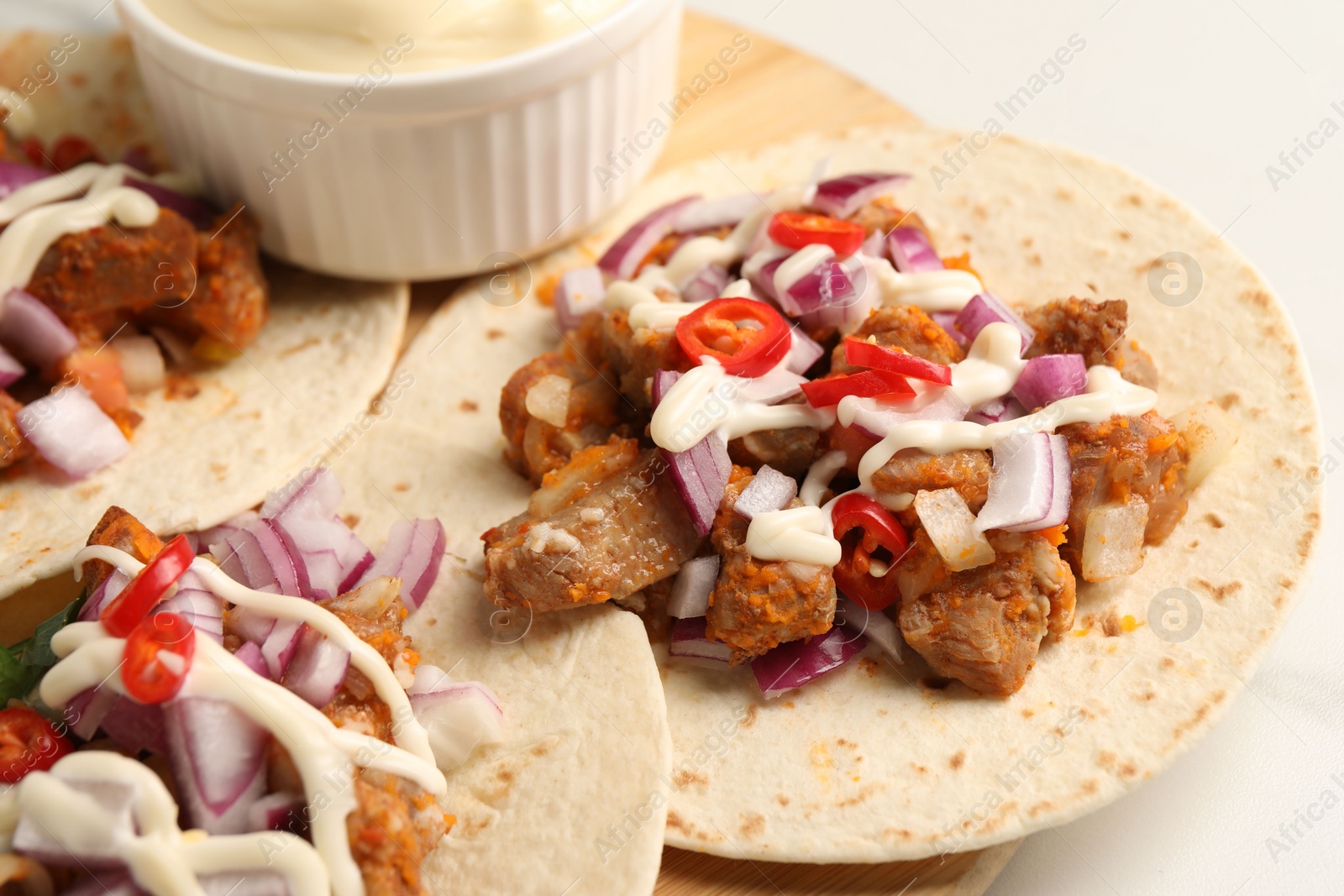 Photo of Delicious tacos with vegetables, meat and sauce on white table, closeup