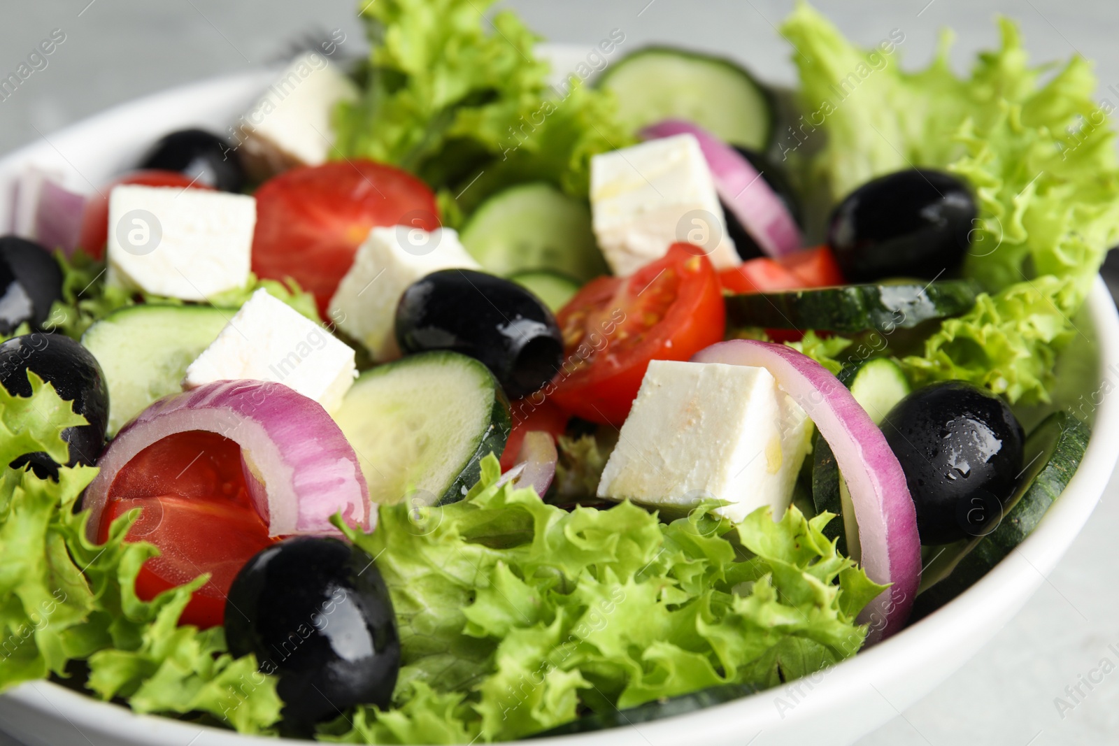 Photo of Tasty fresh Greek salad in  bowl, closeup