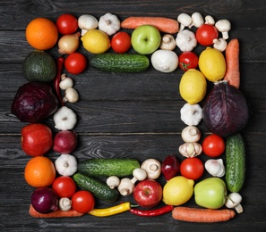 Frame made of fresh delicious vegetables and fruits on wooden table, flat lay. Space for text