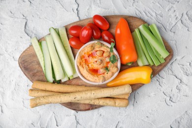 Photo of Board with delicious hummus, grissini sticks and fresh vegetables on light grey textured table, top view