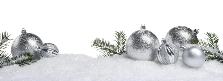 Photo of Beautiful silver Christmas balls and fir tree branches on snow against white background