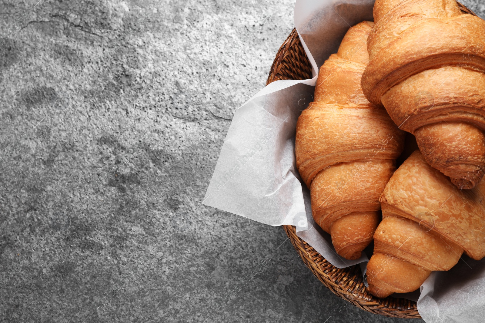 Photo of Tasty fresh croissants on grey table, top view. Space for text