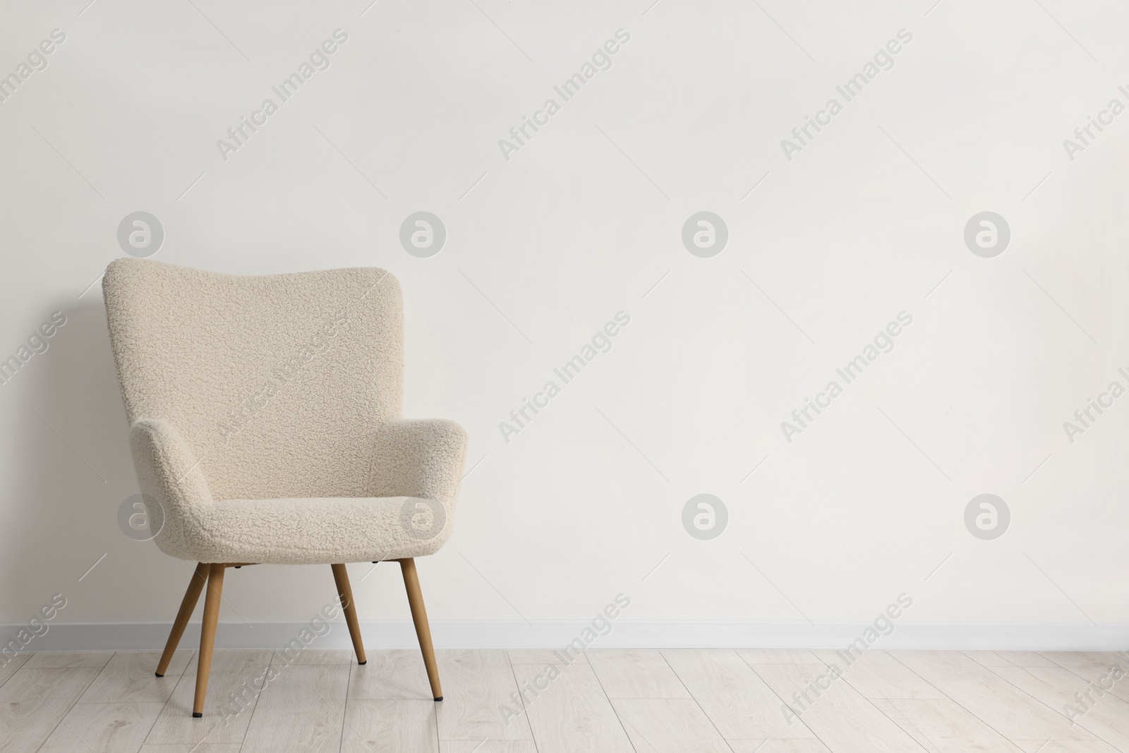 Photo of Comfortable armchair near white wall in room, space for text