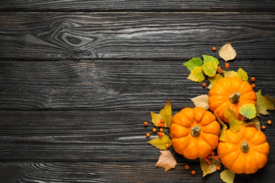 Photo of Flat lay composition with pumpkins and autumn leaves on black wooden table. Space for text