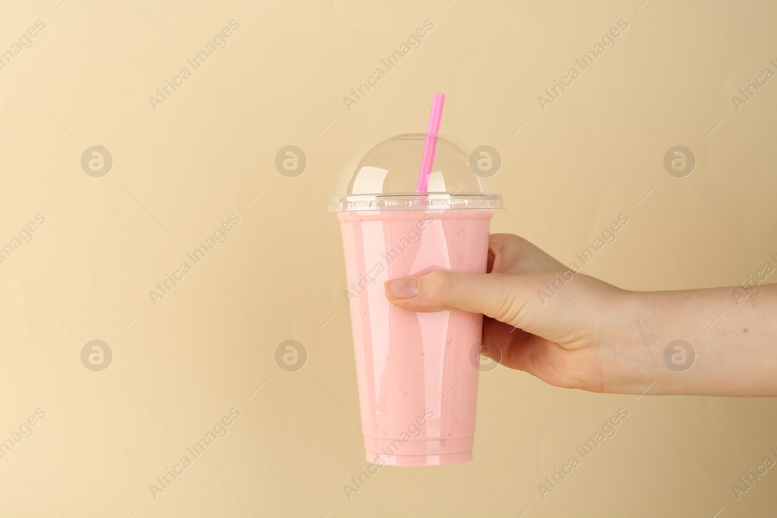 Photo of Woman with plastic cup of tasty smoothie on beige background, closeup