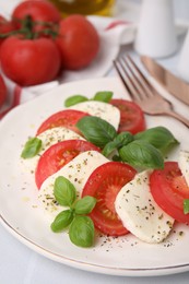 Photo of Caprese salad with tomatoes, mozzarella, basil and spices on white table, closeup